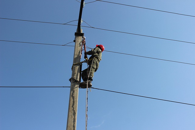 electrician using a fiberglass telescoping ladder to work on outdoor light fixture